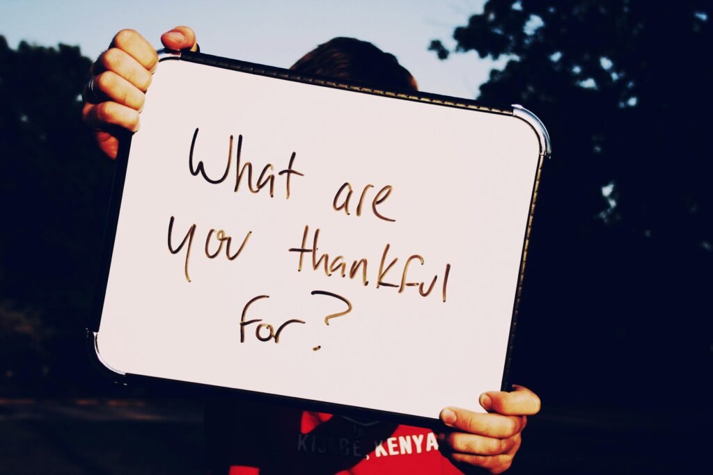 What are you thankful for? Adopt gratitude when feeling stuck in life A person holds a whiteboard asking 'What are you thankful for?' against a dark outdoor background.