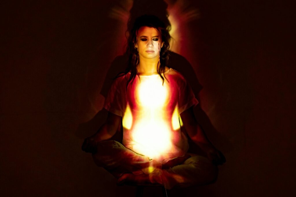 A woman in meditation surrounded by a radiant aura, symbolizing spiritual energy, divine feminine, and enlightenment. ins and outs 2025