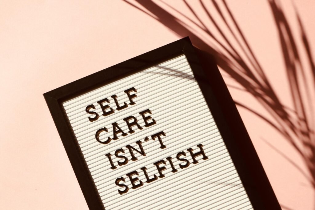 Letter board displaying 'Self Care Isn't Selfish' with artistic shadow on pink background. self-love and self-worth.